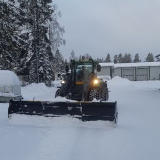 Traktori auraa lumista pihaa